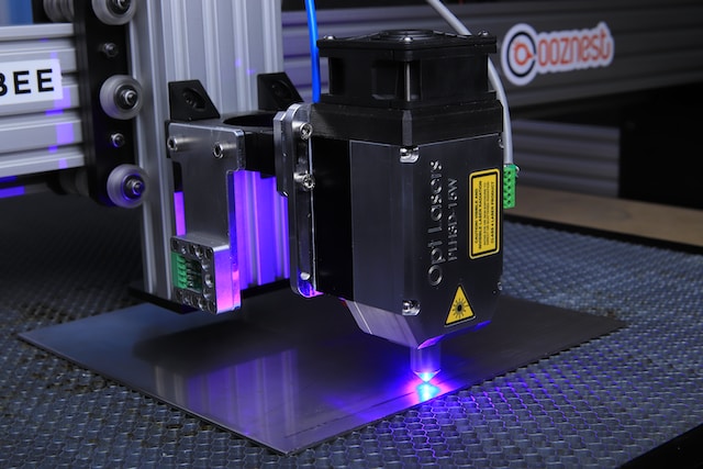 opt-lasers-7NvkRlTzLZE-unsplash (1) Lasermaschine, aus der rosa-blaues Licht dringt